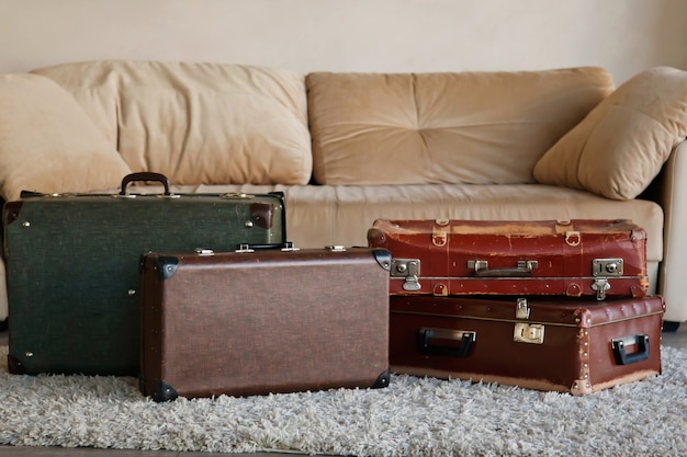 Винтажные старые классические устаревшие кожаные чемоданы в интерьере светлой комнаты у дивана