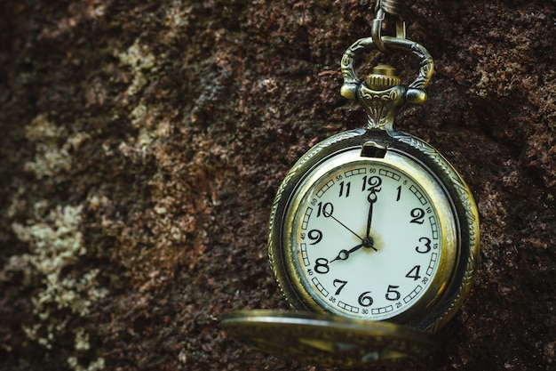 Photo vintage old pocket watch hanged on the rock