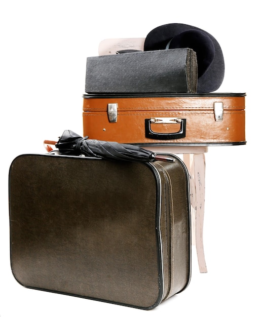 Vintage old travel suitcase and wooden chair with female hat isolated on white