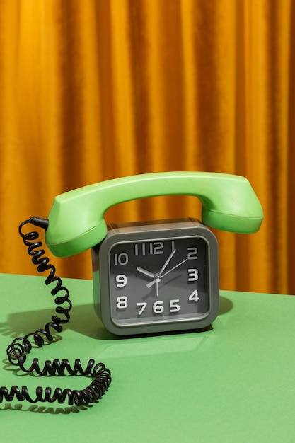 Vintage oude klok met een ouderwetse roterende telefoon op een tafel in een woonkamer met een achtergrond van gordijnen