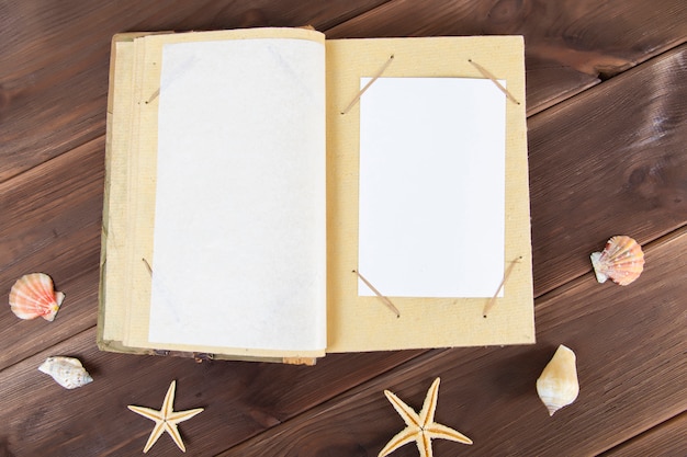 Vintage photo album on wood with seashells.