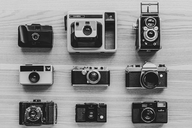 Vintage photo cameras on wooden background Black and white