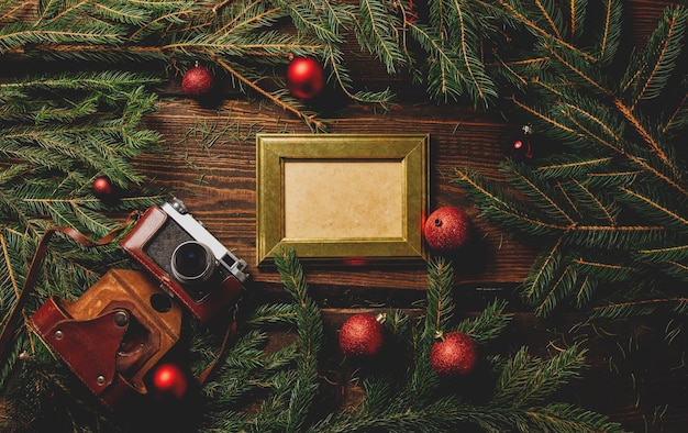 Винтажная фоторамка и фотоаппарат на столе рядом с рождественским украшением