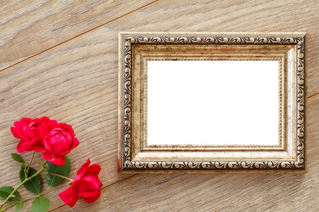 vintage photo frame with copy space and red roses on wooden boards. top view.