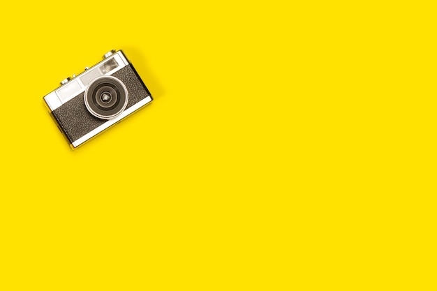 Vintage photographic camera on a yellow background with copy space