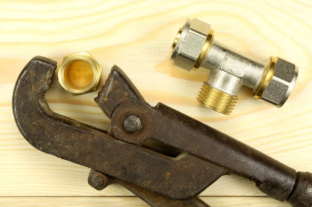 Vintage plumbing tool with modern fittings on wooden table