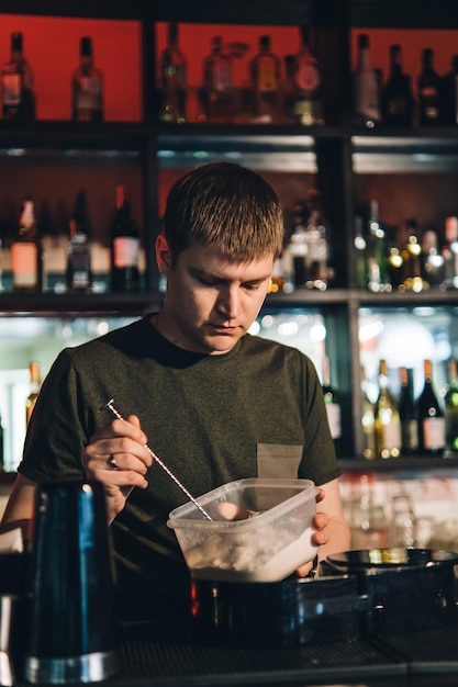 バーでカクテルを作成するバーテンダーのヴィンテージの肖像画アルコール飲料の準備のクローズアップ