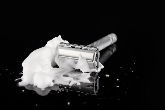 Vintage razor in foam with reflection on a black background Space for text