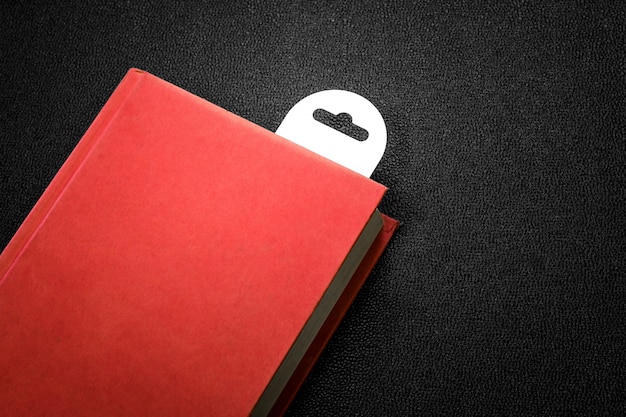 Vintage red book with a bookmark on dark background.