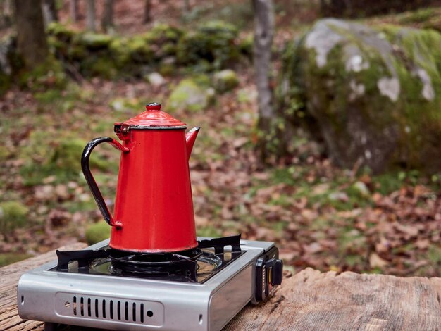 야외 나무 피크닉 테이블에 휴대용 스토브에 빈티지 빨간 커피  ⁇ 비 자연 숲 배경