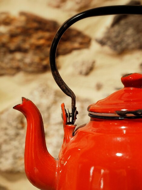 A vintage red enamelware teapot with handle closeup