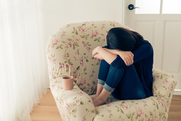 vintage retro film color photo of beauty pretty girl suffered bad things feeling sadness and sitting on sofa crying near home window.