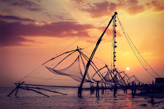 Vintage retro hipster style travel image of Kochi chinese fishnets on sunset Fort Kochin Kochi Kerala India