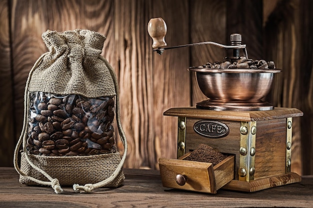 Vintage sack with coffee beans and wooden mill on wood background