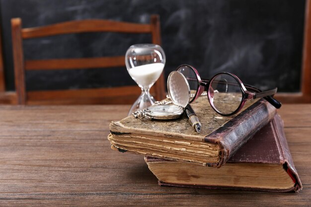 Foto vintage samenstelling van oude boeken brillen en zandloper op houten tafel