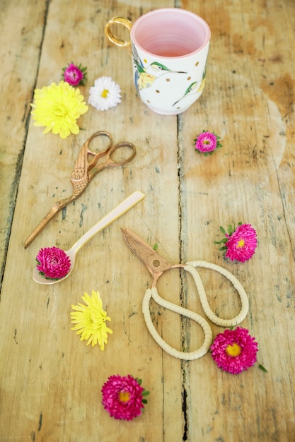 Foto forbici vintage, fiori e una tazza di tè sul tavolo di legno