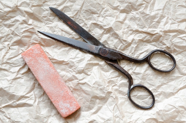 Vintage scissors and red grindstone on the wrapping paper background