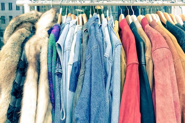 Vintage second hand clothes hanging on shop rack at weekly flea\
market