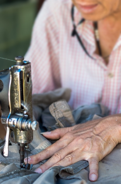 The vintage sewing machine on old man designer blur background, focus on hand