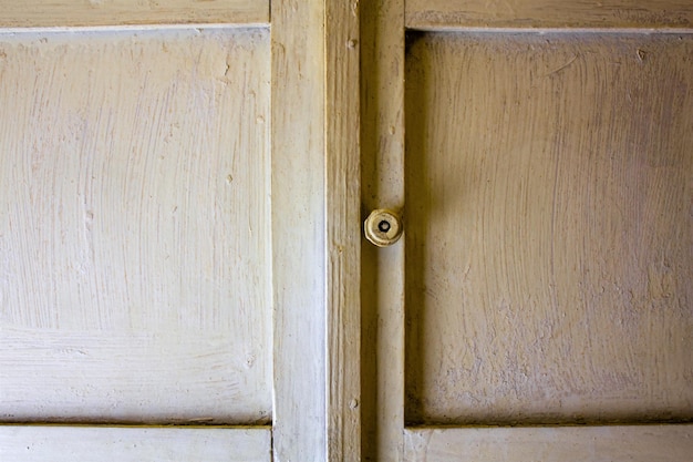 Vintage shabby cabinet with handle texture White doors of an old wardrobe backgroundOld wooden wardrobe backgroundOld abandoned wardrobe doors