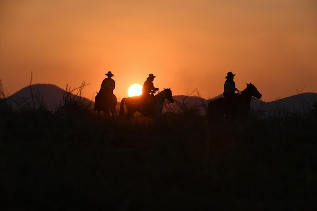 Vintage and shadow of a group of cowboys galloping on horseback at sunset