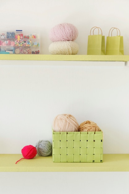 ウールのボールとボタンが付いた編み物用具のヴィンテージの棚