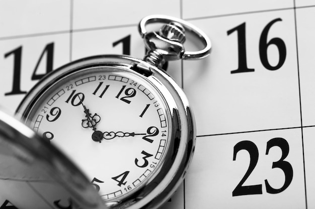 日付がクローズアップされたカレンダーページに敷設されたヴィンテージの銀の懐中時計