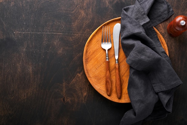 Vintage silverware Rustic vintage set of wooden spoon and fork on wooden platter on black wooden background Empty dishes Top view Mock up