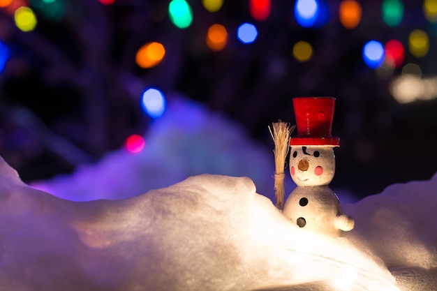 Foto pupazzo di neve vintage nella neve su sfondo notturno con luci di natale