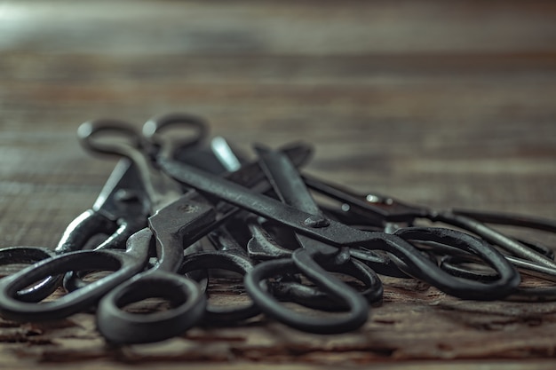 Vintage steel scissors on wooden table background. Old-fashioned instruments for florist, barber, seamstress. History, professional collection of equipment, beauty of workplace. Vintage, retro style.