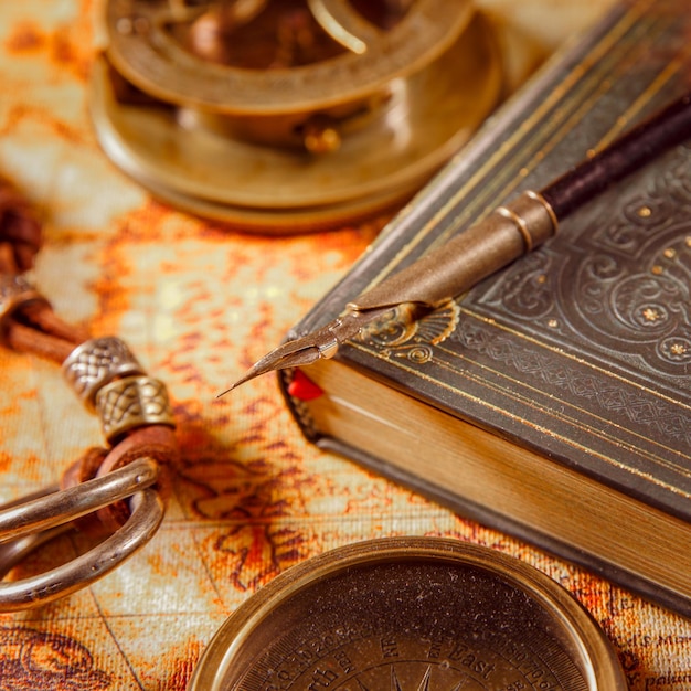 Vintage still life - magnifying glass, pocket watch, old book and goose quill pen lying on an old map in 1565.