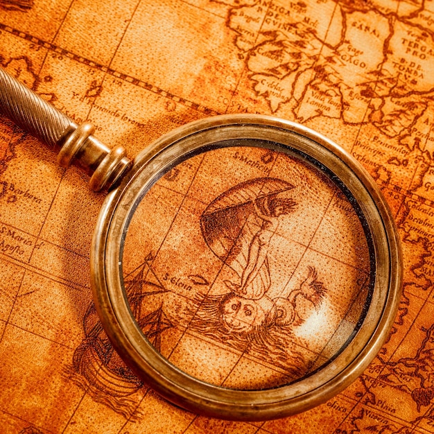 Vintage still life. Vintage magnifying glass lies on an ancient world map in 1565.