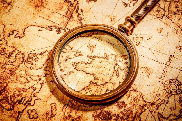 Vintage still life. Vintage magnifying glass lies on an ancient world map