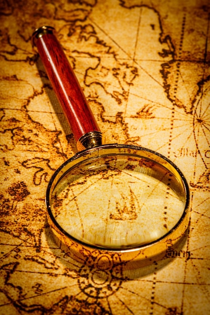 Vintage still life. Vintage magnifying glass lies on an ancient world map