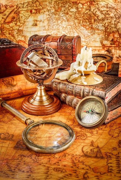 Vintage still life. vintage magnifying glass lies, pocket watch, old book and armillary sphere on an ancient world map in 1565