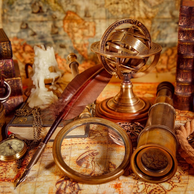 Vintage still life. Vintage magnifying glass lies, pocket watch, old book and astrolabe on an ancient world map in 1565.