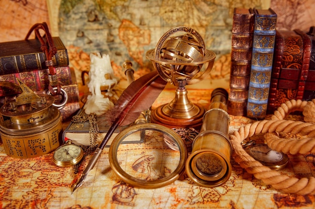 Vintage still life. Vintage magnifying glass lies, pocket watch, old book and astrolabe on an ancient world map in 1565.