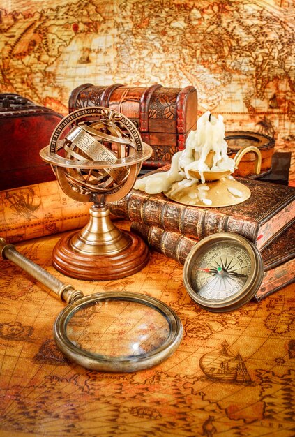 Vintage stilleven. vintage vergrootglas ligt, zakhorloge, oud boek en armillairbol op een oude wereldkaart in 1565.