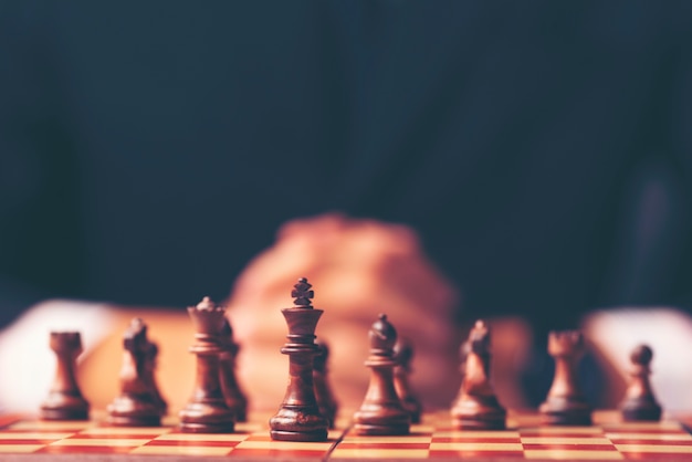 Vintage style image of a businessman with clasped hands planning strategy with chess