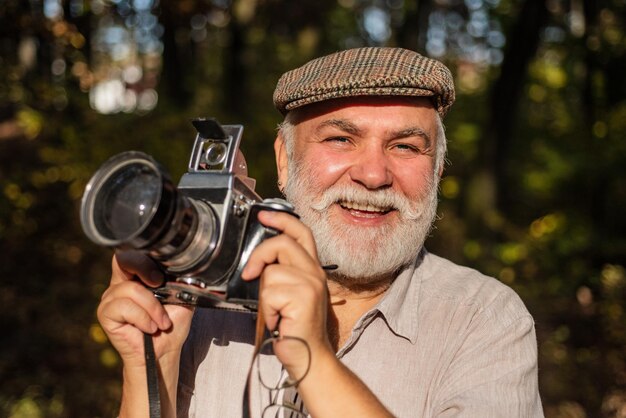 Stile vintage viaggi stile di vita vacanze concetto fotografo uomo in possesso di una macchina fotografica vintage uomo barbuto stile di vita e concetto di viaggio dammi un sorriso il concetto di macro fotografia naturalistica