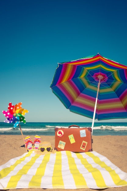 Vintage suitcase and beach items against blue sea and sky