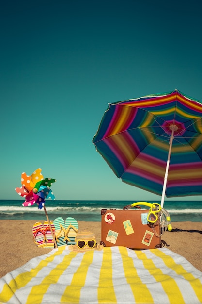 Vintage suitcase and beach items against blue sea and sky