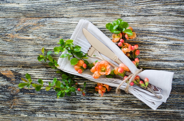 Vintage table setting with delicate flowers on rustic shabby table.