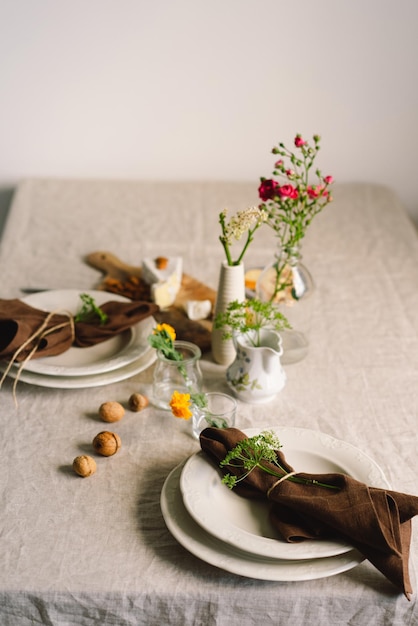 리넨 냅킨과 꽃 장식이 있는 빈티지 테이블 설정 햇살 아래 아침에 아늑한 차분한 식사를 닫습니다