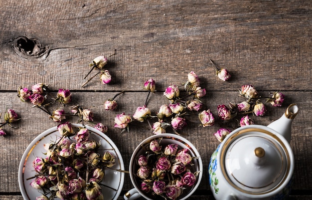 Vintage teapot and cup with blooming tea flowers on wood