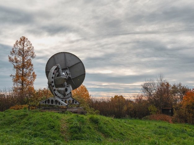 Vintage telescope a large satellite dish on a background of observation forest and cloudy sky early morning radar in the past Technology concept search for extraterrestrial life wiretap of space