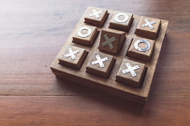 Vintage Tic Tac Toe wooden board game on wooden top table with selective focusing, planing and thinking conceptual