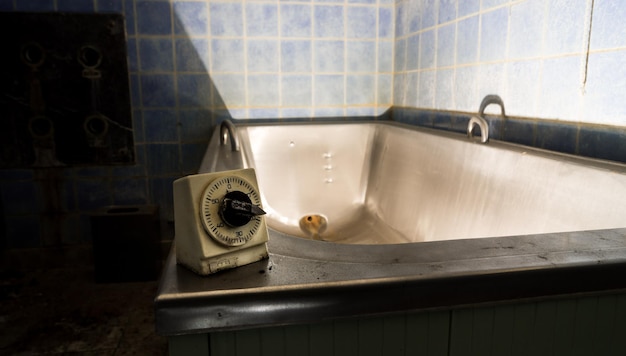 Фото Винтажный таймер на ванне в заброшенной ванной