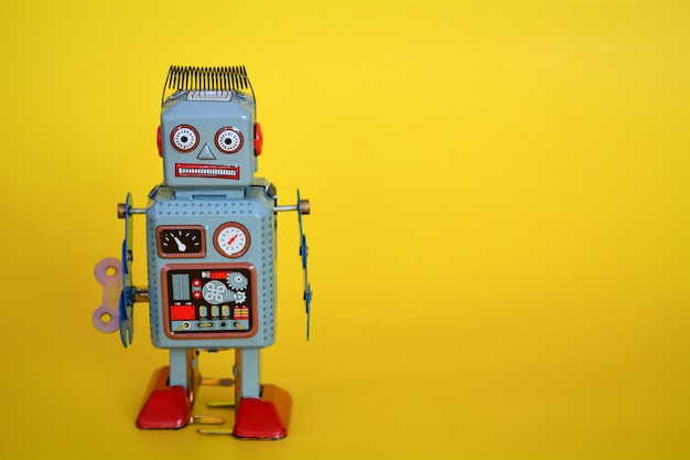 Vintage tin toy robot isolated on a yellow background.