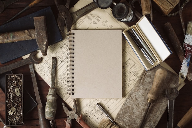 Photo vintage tool, notebook on the dark wooden background.